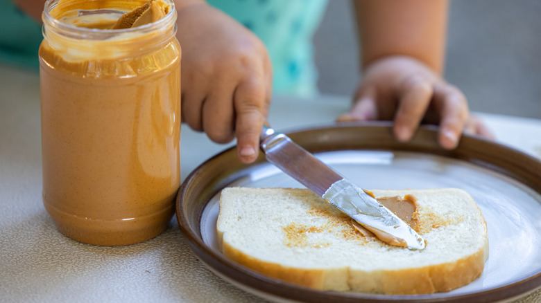 Child's hands spreading peanut butter on toast