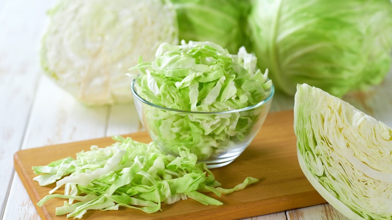 shredded cabbage in bowl beside whole heads