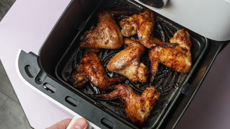Cooked chicken wings inside an air fryer drawer