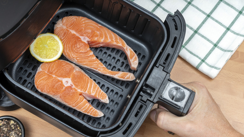 Two salmon fillets in an air fryer basket