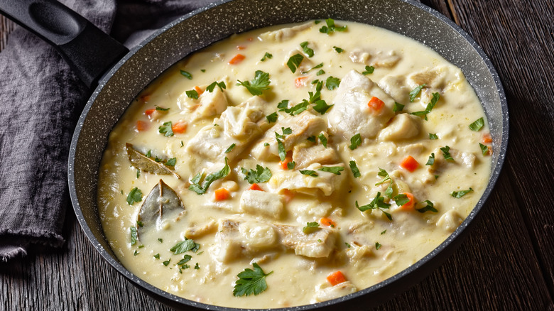 poached fish in milk base sauce with vegetables, spices and herbs in a pan