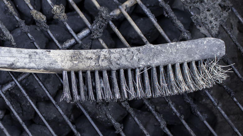 Sooty wooden brush with frayed metal bristles.