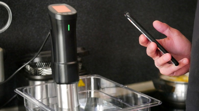 hand controls sous vide machine with a smartphone