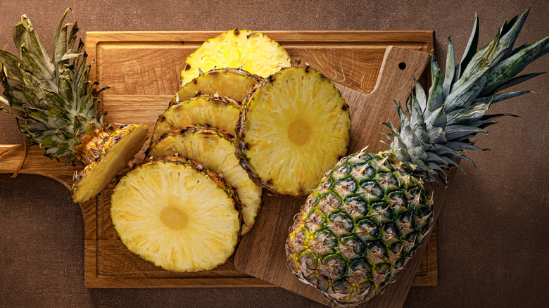 Sliced and whole pineapples on a wooden board
