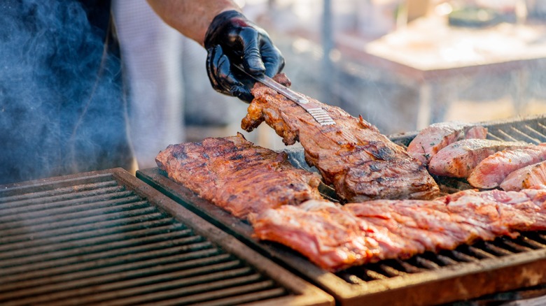 hand flips ribs on bbq grill