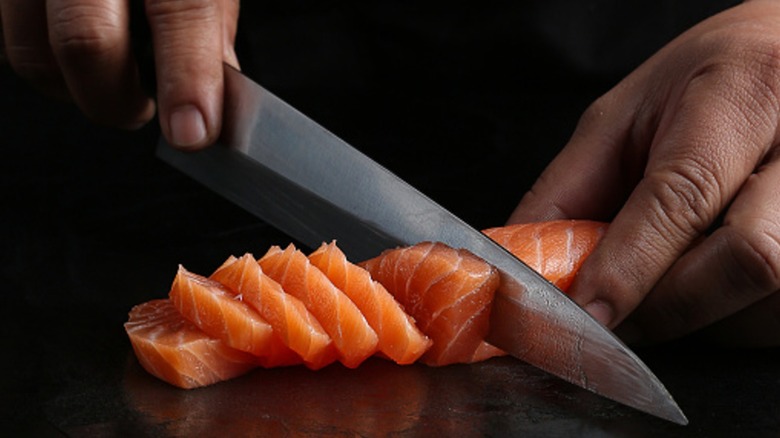 hands delicately chop slices of fresh salmon