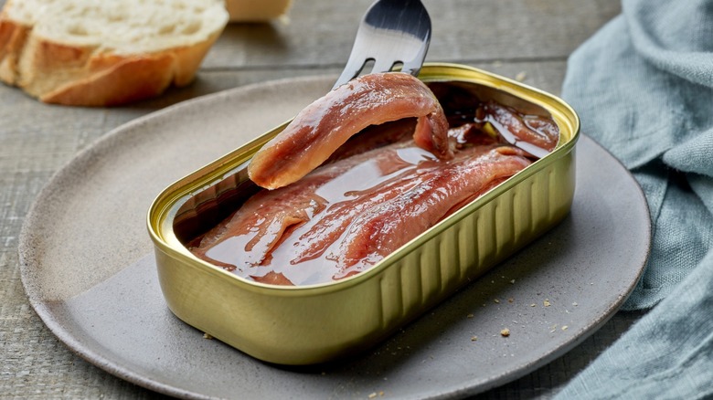 tinned anchovies with fork on plate