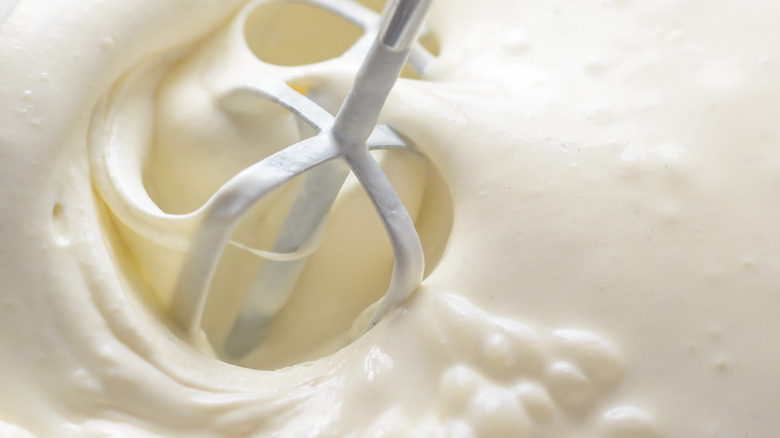 Hand mixer beaters moving through heavy cream. 