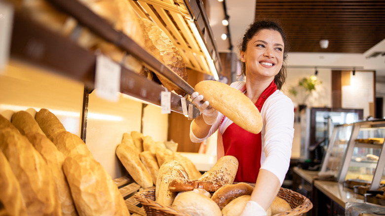A woman holding a basket of bread in a bakery