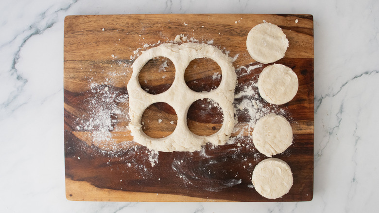 Round cookie cutter pieces of dough removed from a square of dough