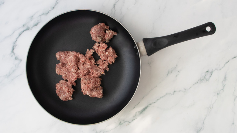 A large skillet filled with raw breakfast sausage