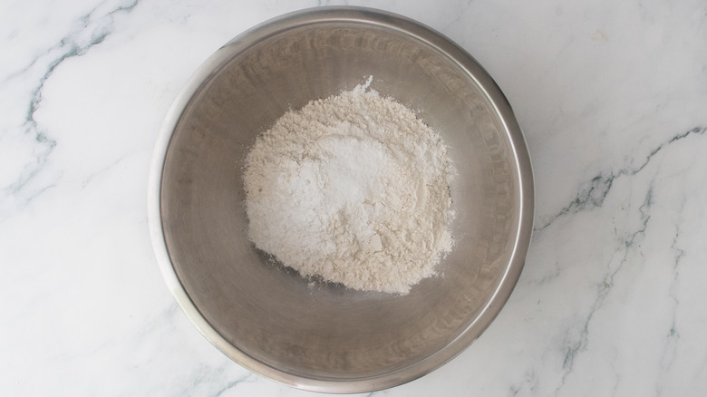 A large metal bowl filled with dry baking ingredients