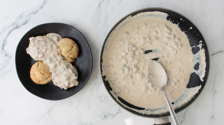Biscuits and gravy on plate next to skillet of sausage gravy