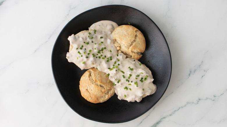 A plate of biscuits and gravy sprinkled with fresh chopped chives