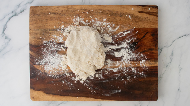 A folded piece of dough on a floured wood cutting board