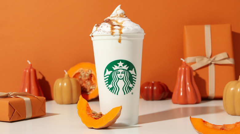 Starbucks drink against orange background with decorative gourds.