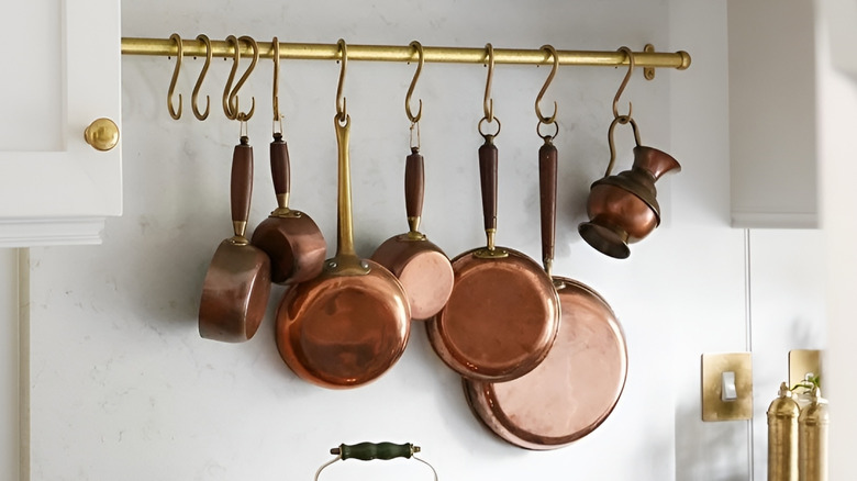 Rack of copper pots and pans hanging above stove.