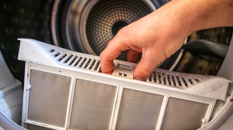 a hand pulls lint filter from dryer