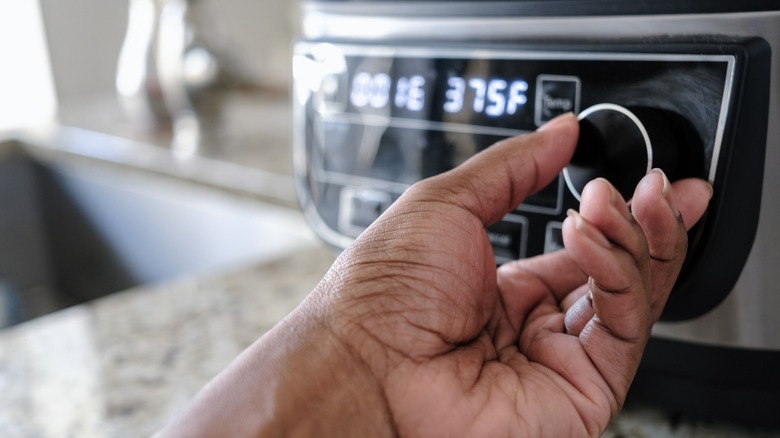 hand adjusts settings on air fryer
