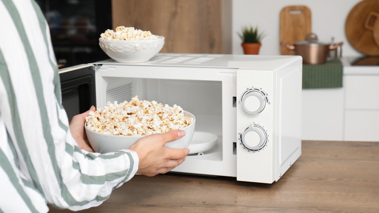 hands pull a bowl of homemade popcorn from the microwave