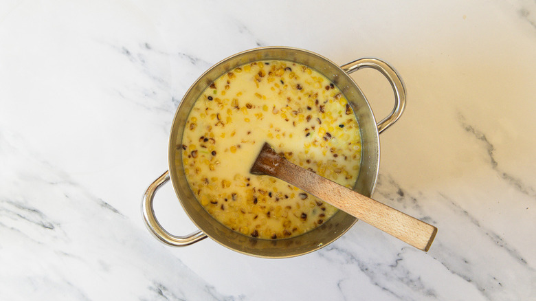 Soup with roasted corn and wooden spoon