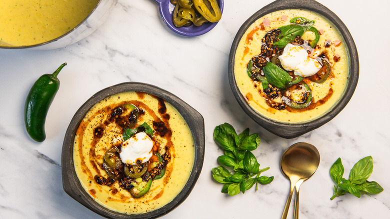 Two bowls of corn chowder with various garnishes