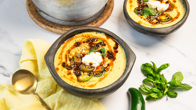 Two bowls of corn chowder with toppings