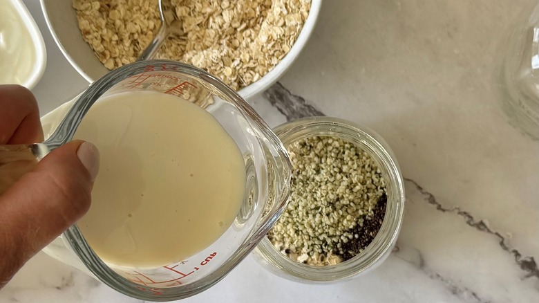 pouring milk into mason jar with oats