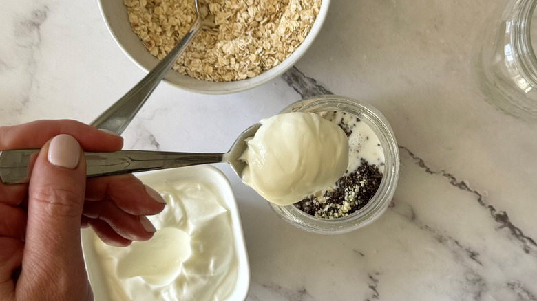scooping yogurt into mason jar with oats