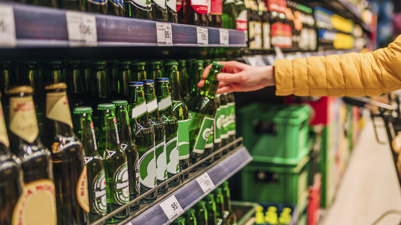 Customer picking a bottle of beer off a supermarket shelf