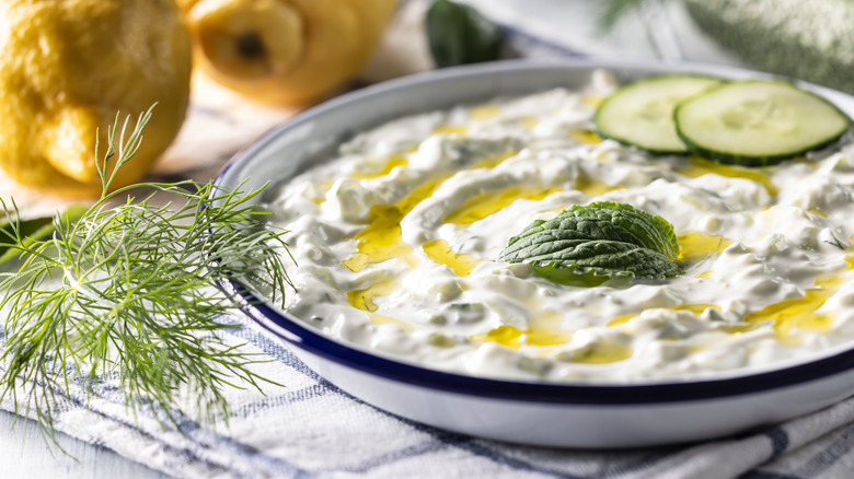 Tzatziki served in a bowl topped with cucumber, olive oil, and fresh herbs.