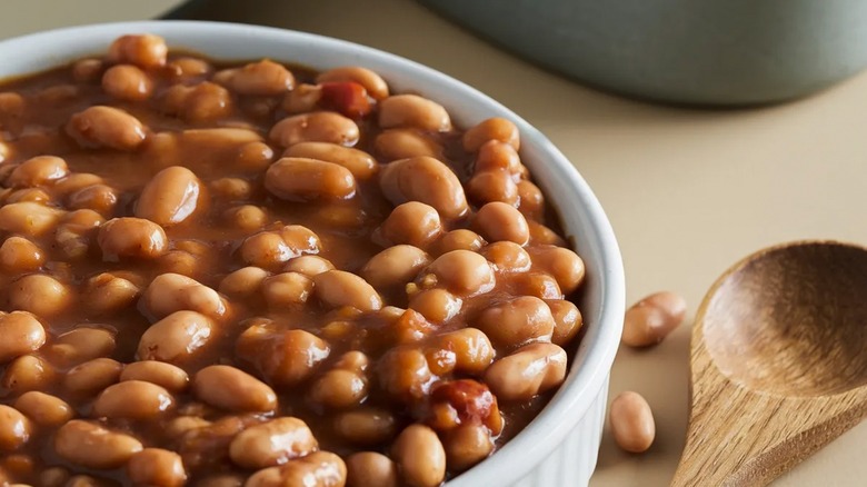 close-up of hearty baked beans with wooden spoon