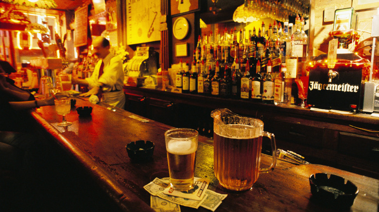 a low lit bar with bartender at beer tap and beer on counter