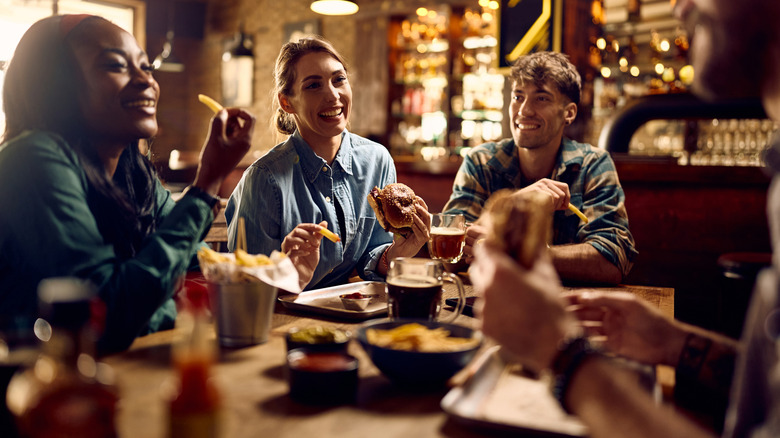 group of people drinking beer and eating food at table