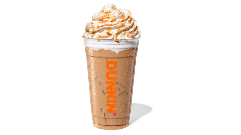 Plastic cup of Dunkin' Pumpkin Spice Latte topped with whipped cream