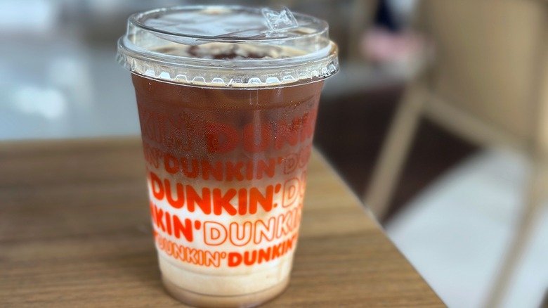 Landscape mode of unstirred iced latte from Dunkin' Indonesia, showcasing rich espresso layered with chilled milk and ice.