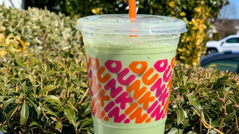 Plastic cup of Dunkin' Iced Matcha Latte outside