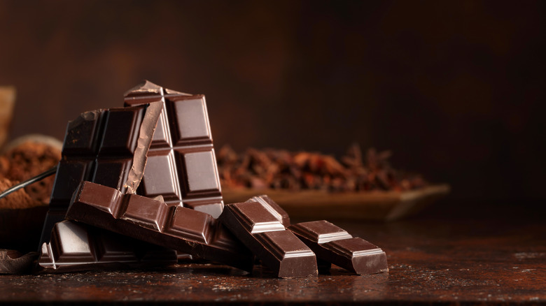 Dark chocolate bar and cocoa on table, dark background.