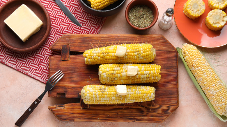 Corn on the cob with butter on wooden board.