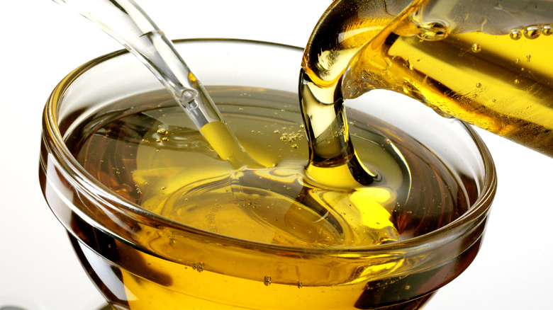 Agave syrup being poured from a jug into a clear glass bowl