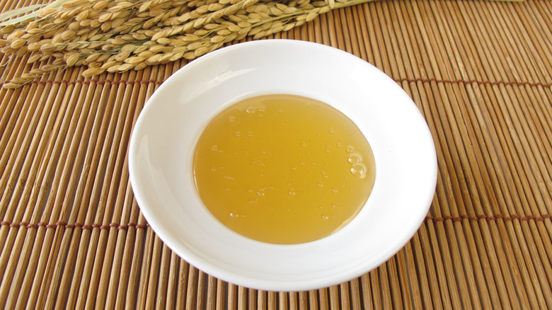 A bowl of rice syrup and panicles on a bamboo mat