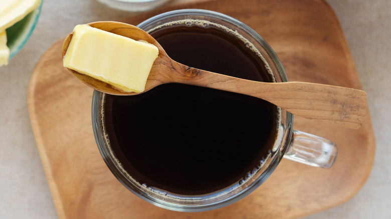 A knob of butter on a spoon over a cup of coffee