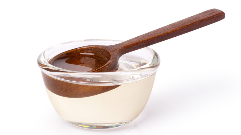A thick wooden spoon in a bowl of simple syrup