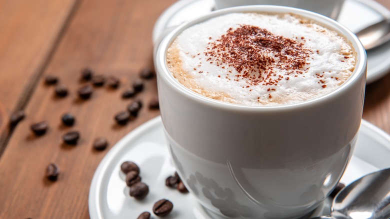 Cup with hot cappuccino with foam and cocoa powder dusting