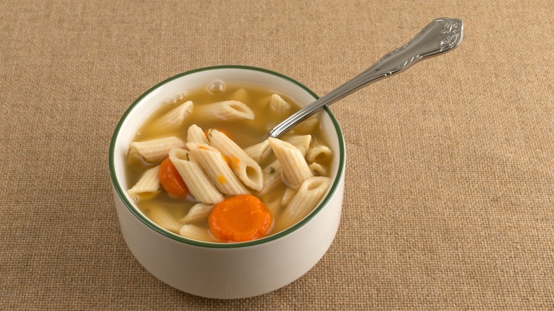brothy cup of chicken noodle soup with spoon