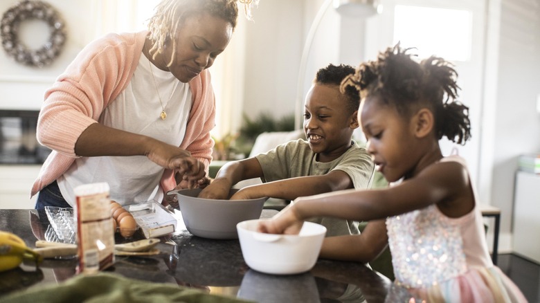 Mother and two children baking cookies in a kitchen.