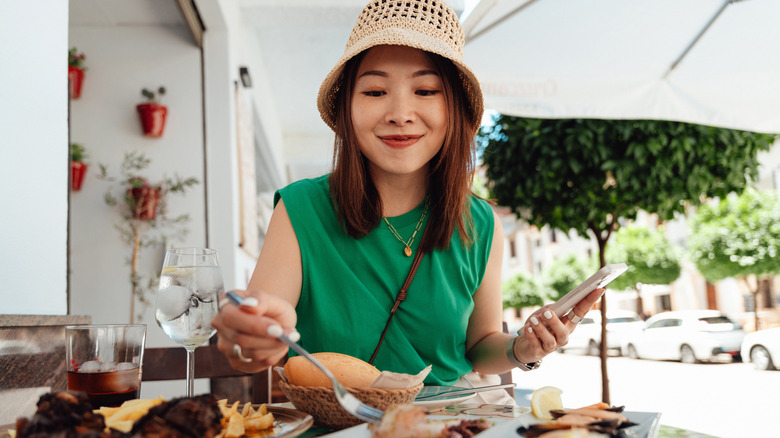 Smiling woman eating tapas with fork at outdoor table