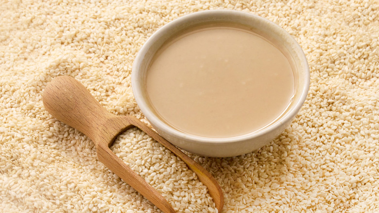 A bowl of tahini sitting in sesame seeds