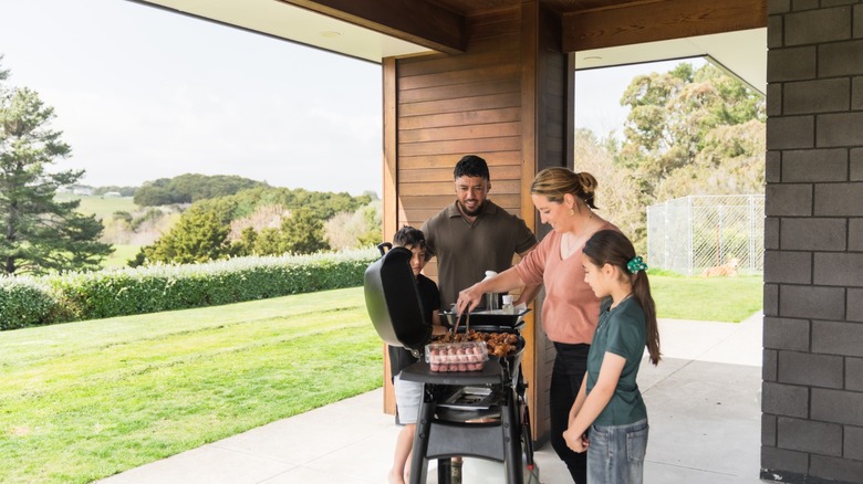 a family gathers around a grill for a cookout