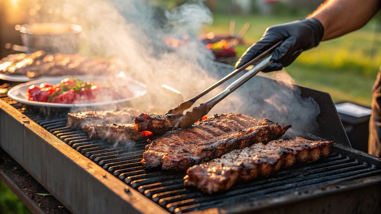 a man cooks barbecue meat on a grill